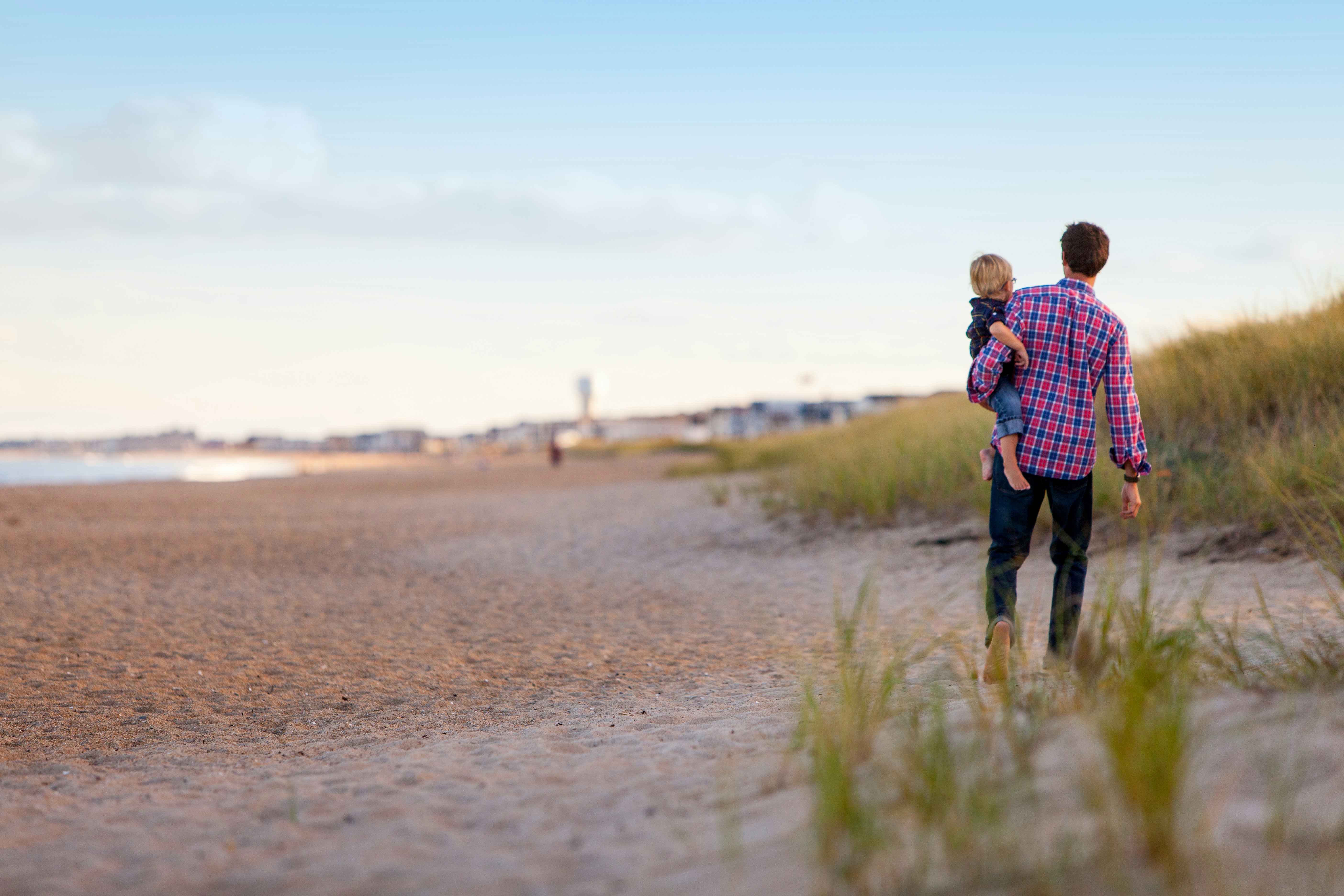 person carrying child while walking in front of oceon